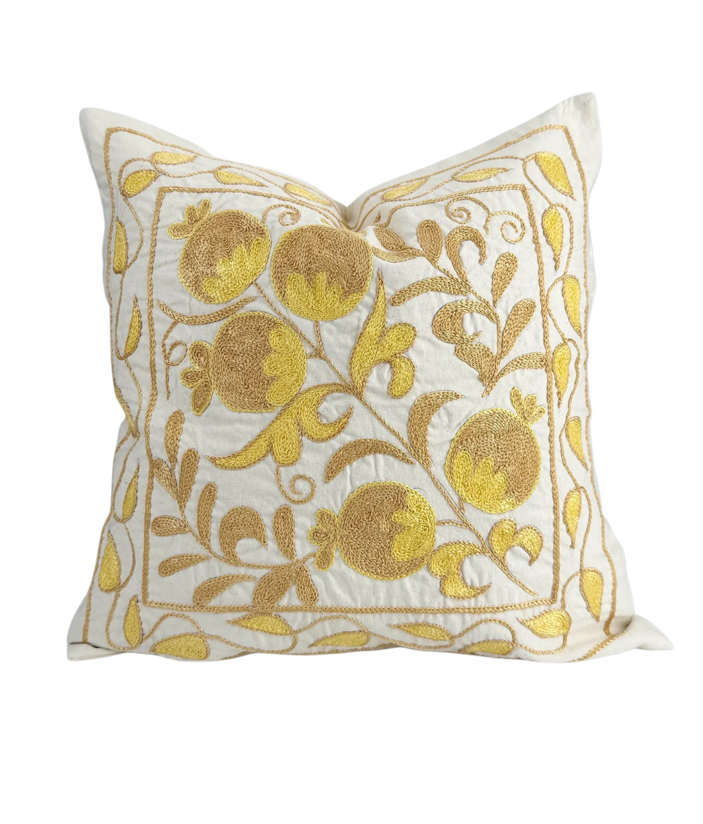 Decorative pillow with gold floral embroidery on a white background
