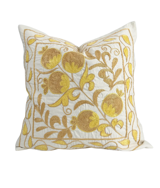 Decorative pillow with gold floral embroidery on a white background