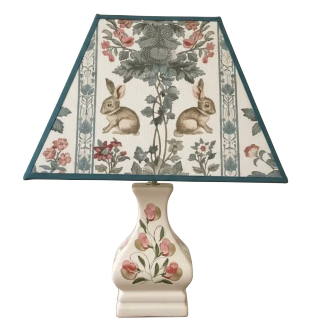 Decorative lamp with floral and rabbit design on the shade against a white background