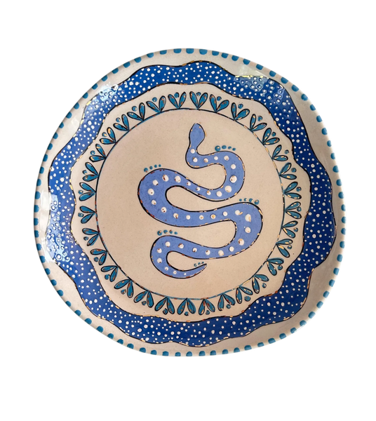Ceramic plate with blue snake design on a beige background