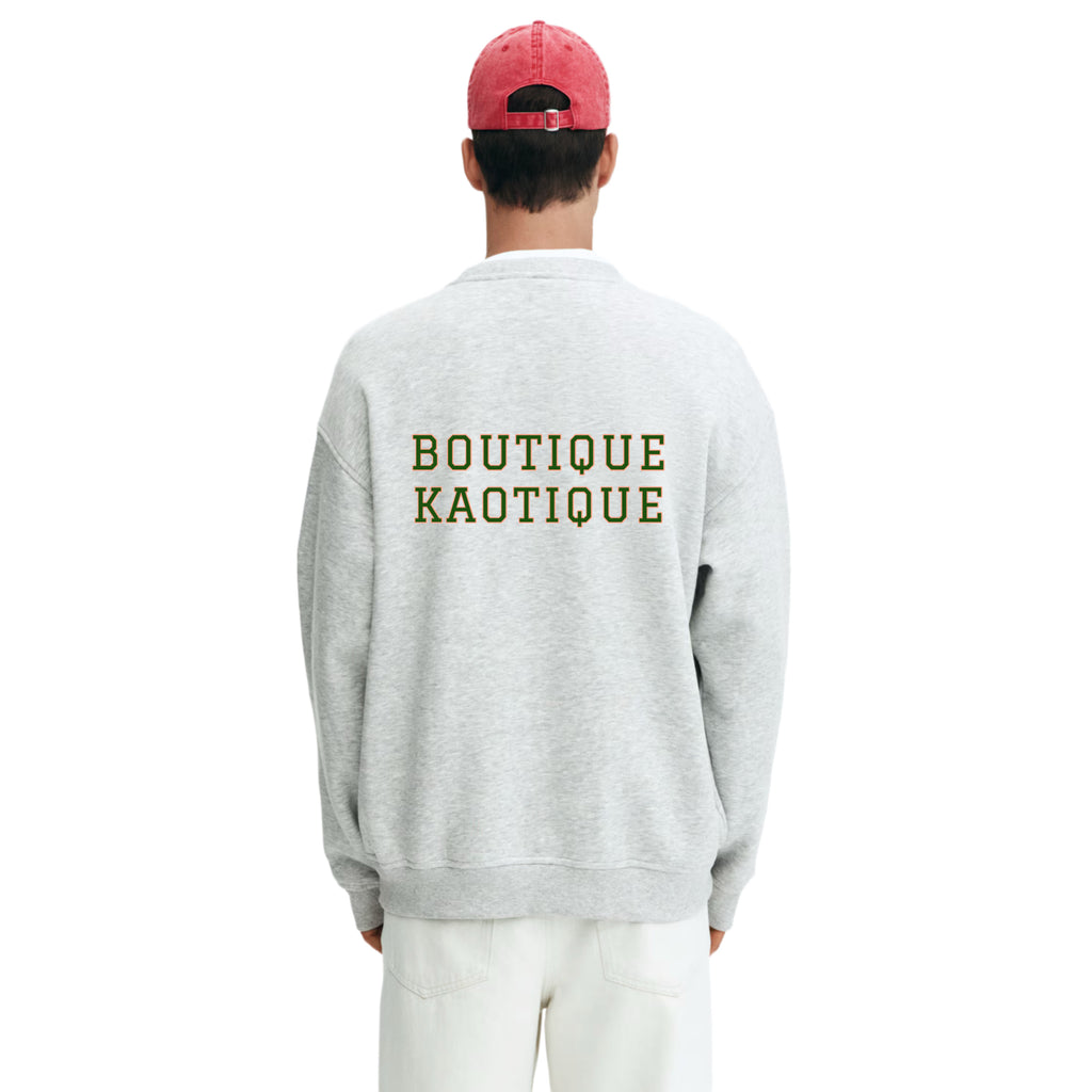 Person wearing a gray sweatshirt with 'Boutique Kaotique' text on the back, standing against a white background. It Will All Work Out sweatshirt — grey 320gsm organic cotton charity sweatshirt, unisex fit, multi-cause made-to-order