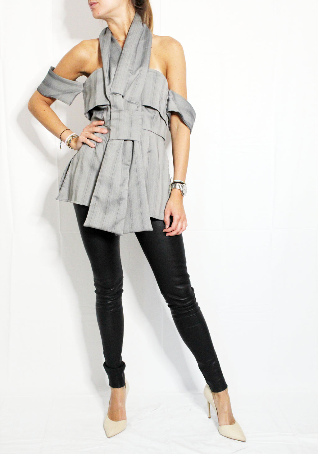 Woman wearing a gray off-shoulder top, black leggings, and white shoes on a white background. Indonesian cut-out shirt — handmade designer shirt with cut-out detail from Maryallé Jakarta, fitted, limited edition