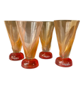 Three Kosta Boda glasses with orange and red design on a white background