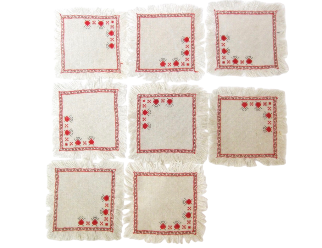 Set of eight white napkins with red floral patterns on a white background