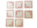 Set of eight white napkins with red floral patterns on a white background
