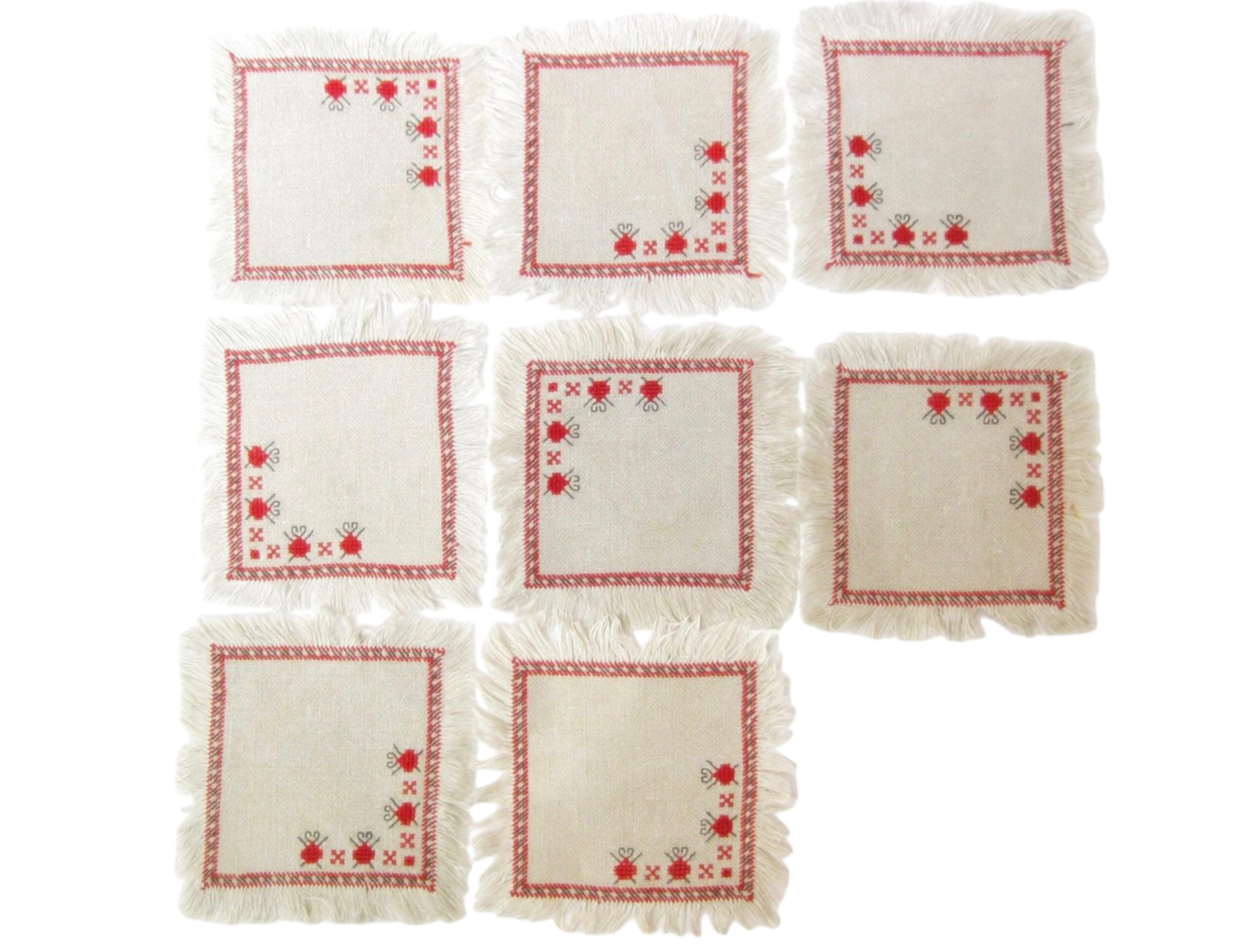 Set of eight white napkins with red floral patterns on a white background