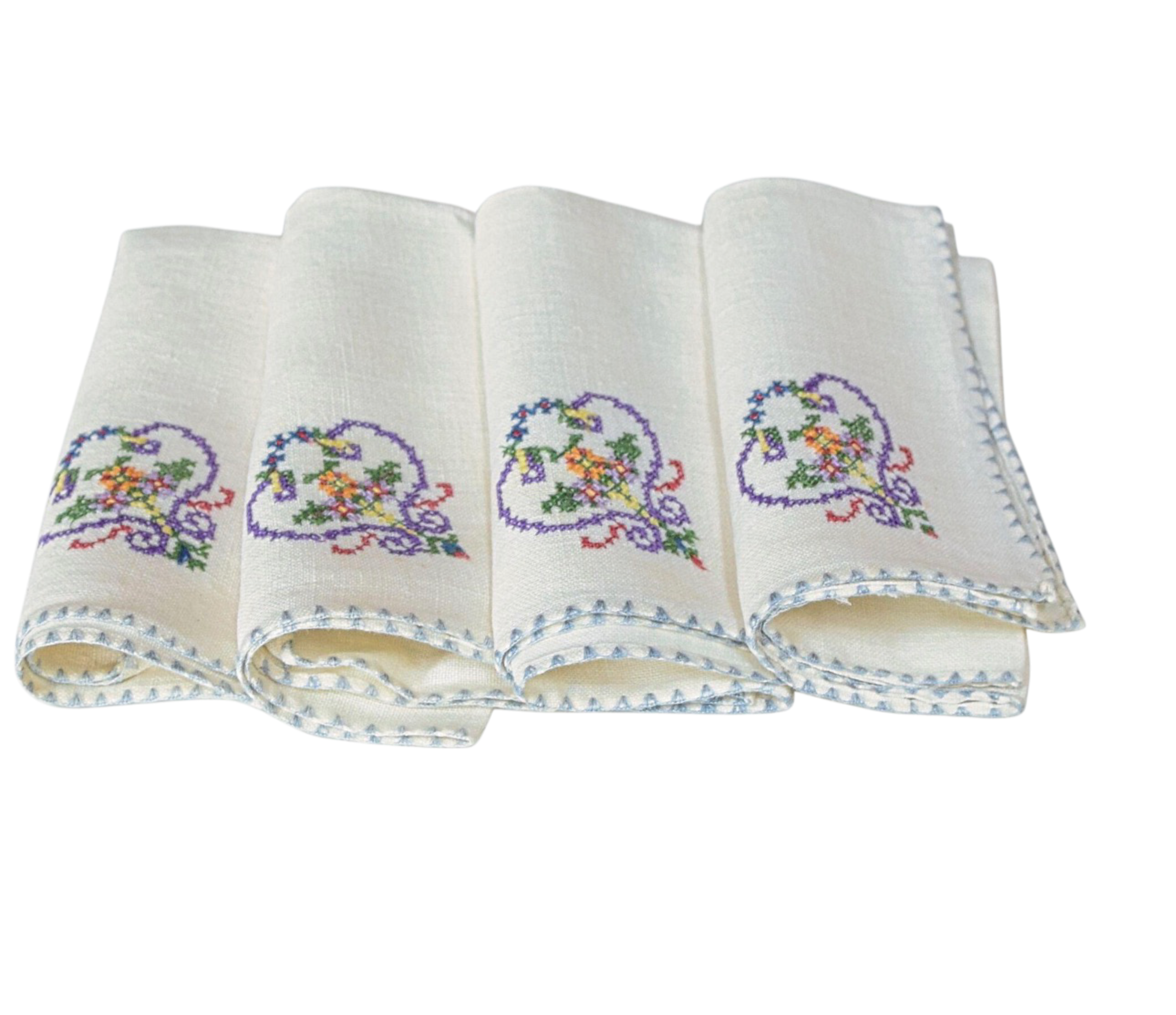 Set of four folded white napkins with embroidered designs on a white background