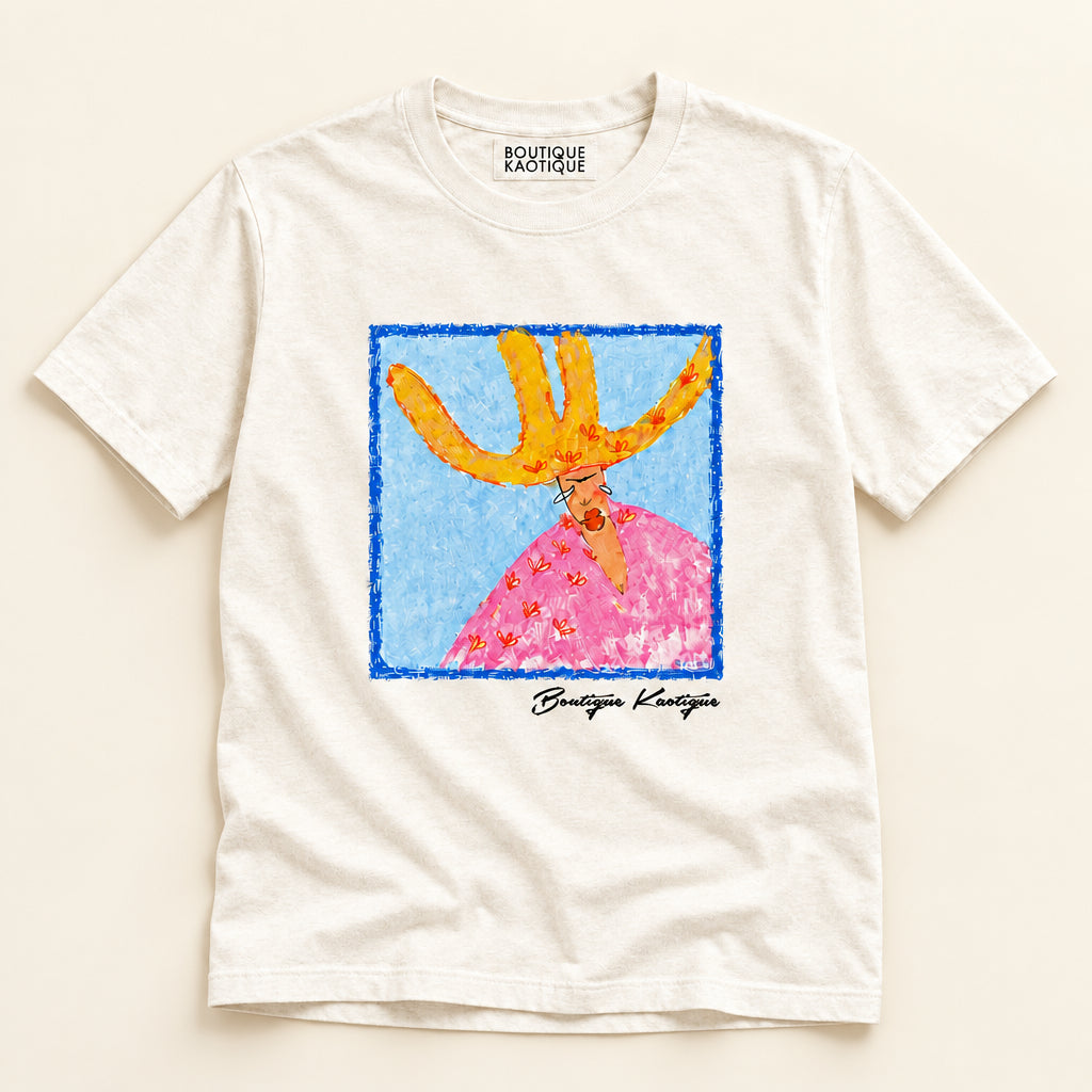 T-shirt with a colorful graphic of a person with antlers and a pink dress on a white background. Wearing All My Hats affirmation tee — white organic cotton t-shirt with playful print, unisex fit, gender equality charity