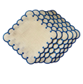 Set of beige placemats with blue scalloped edges on a white background