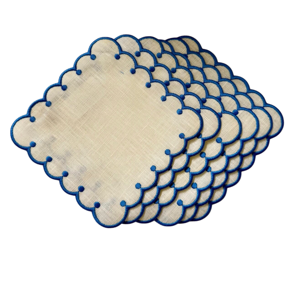 Set of beige placemats with blue scalloped edges on a white background