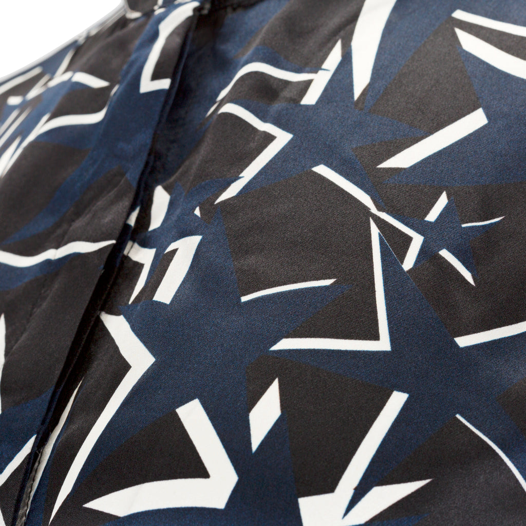 Close-up of a patterned fabric with black and white geometric shapes on a blue background. Starry Night dress — handmade designer dress with starry print from Hanout Boutique Marrakech, fitted, limited edition occasion piece