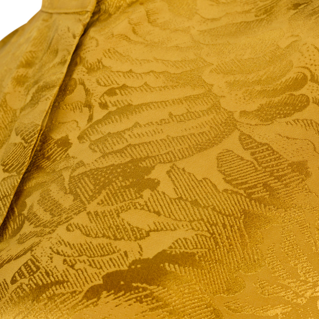 Close-up of a textured gold fabric with a pattern. Golden Hour dress — handmade yellow gold designer dress from Hanout Boutique Marrakech, fitted, limited edition occasion piece