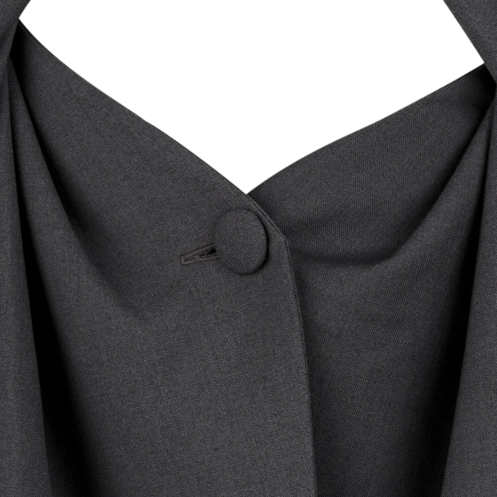 Close-up of a dark gray fabric with a button on a white background. Unique ultra feminine cut blazer — handmade designer blazer from Patrick Owen Jakarta, fitted, limited edition occasion piece