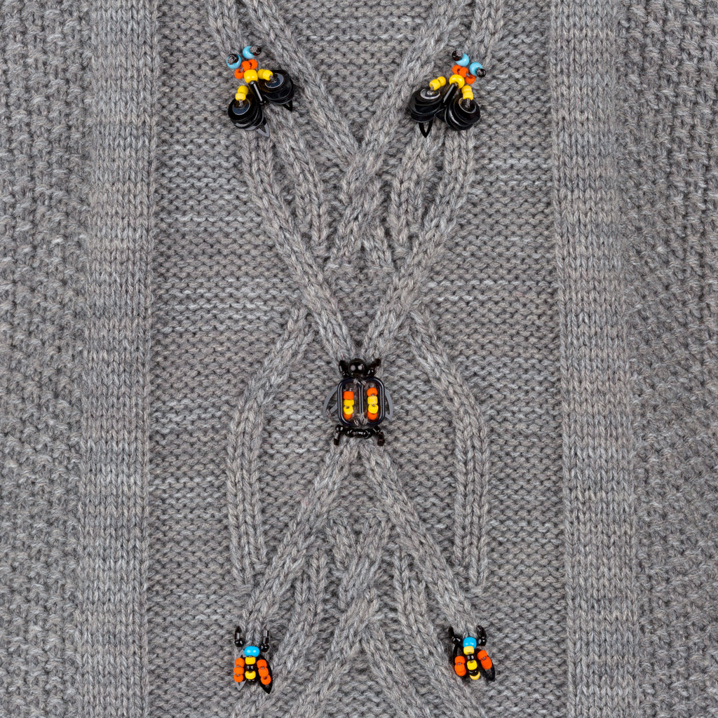 Close-up of a gray knitted fabric with decorative black and orange beads. Wool embroidered vest — handmade wool designer vest with hand-embroidery from Patrick Owen Jakarta, relaxed fit, limited edition