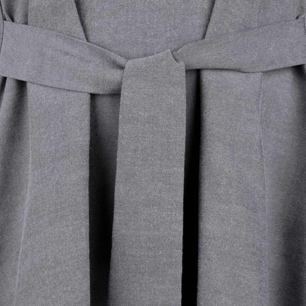 Close-up of a gray dress with a belt. Indonesian asymmetrical blouse — handmade asymmetric designer blouse from Maryallé Jakarta, fitted, limited edition piece