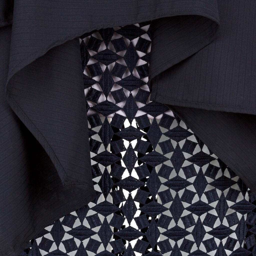 Close-up of a patterned tie with a dark shirt background. Indonesian-inspired lace skirt — handmade lace designer skirt from Maryallé Jakarta, fitted, limited edition occasion piece