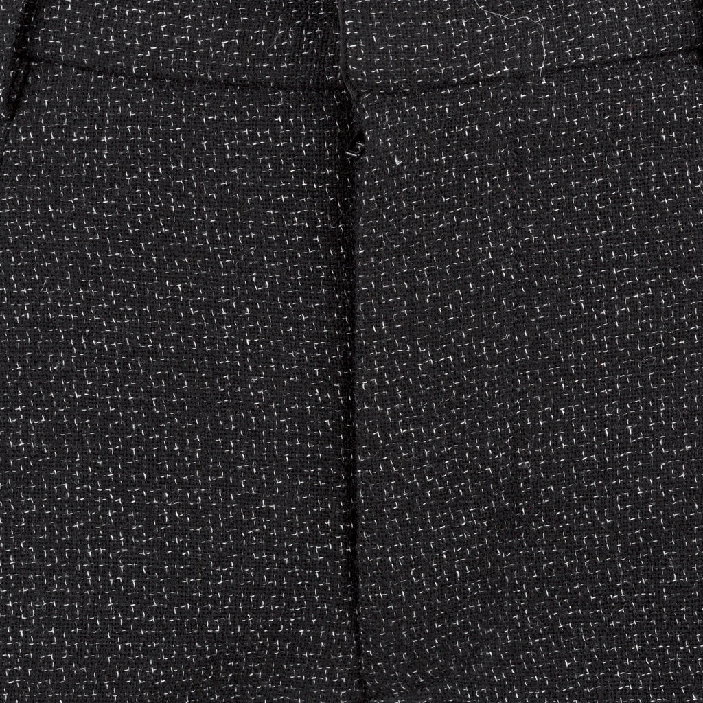 Close-up of black textured fabric with a subtle pattern. Flared wool trousers — handmade designer flared wool trousers from Patrick Owen Jakarta, relaxed fit, limited edition winter piece
