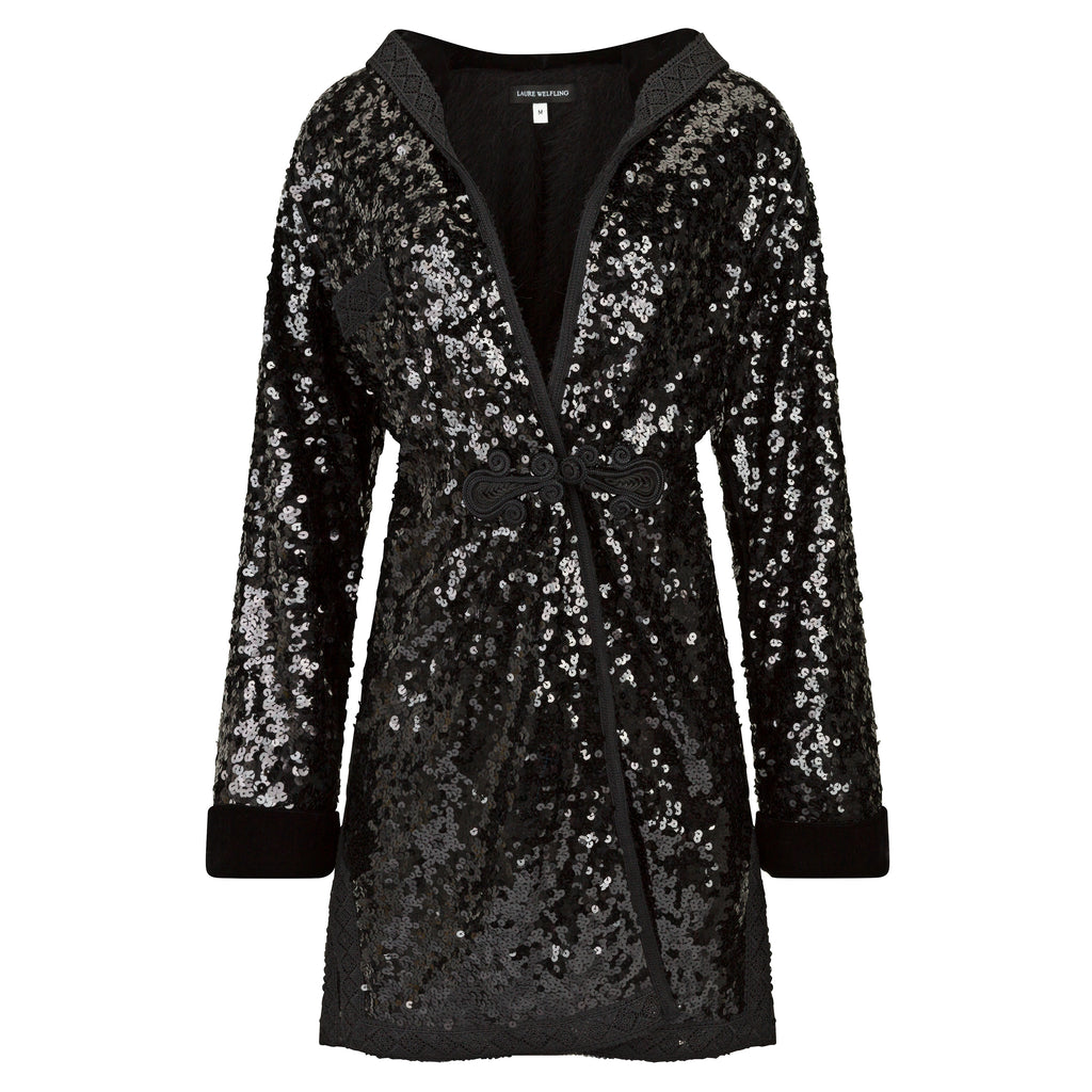 Black sequin coat with a hood on a white background. Black sequins embroidered coat — black designer coat with hand-stitched sequin embroidery from Laure Welfling Marrakech, limited edition