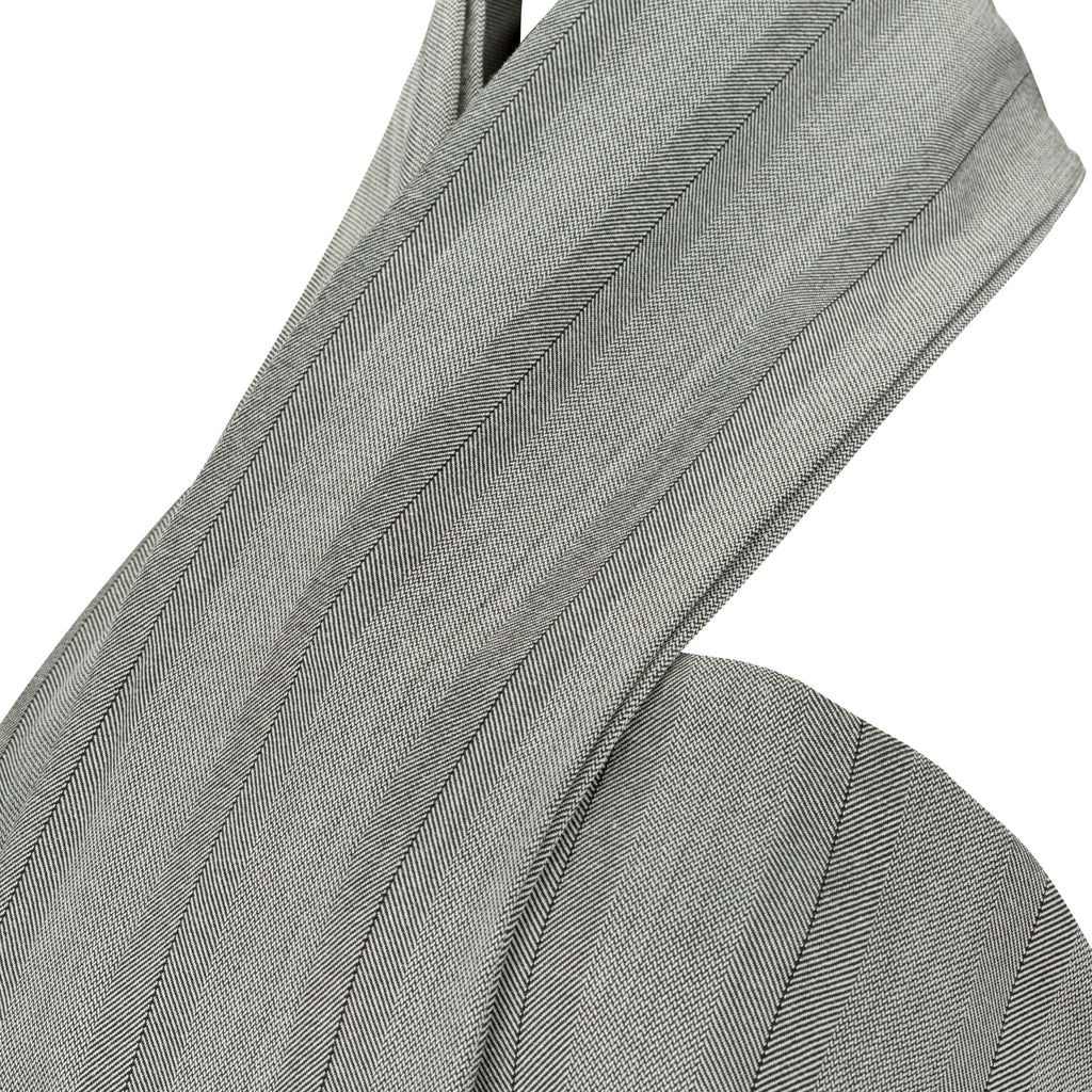 Close-up of a gray fabric with a subtle pattern on a white background. Indonesian cut-out shirt — handmade designer shirt with cut-out detail from Maryallé Jakarta, fitted, limited edition