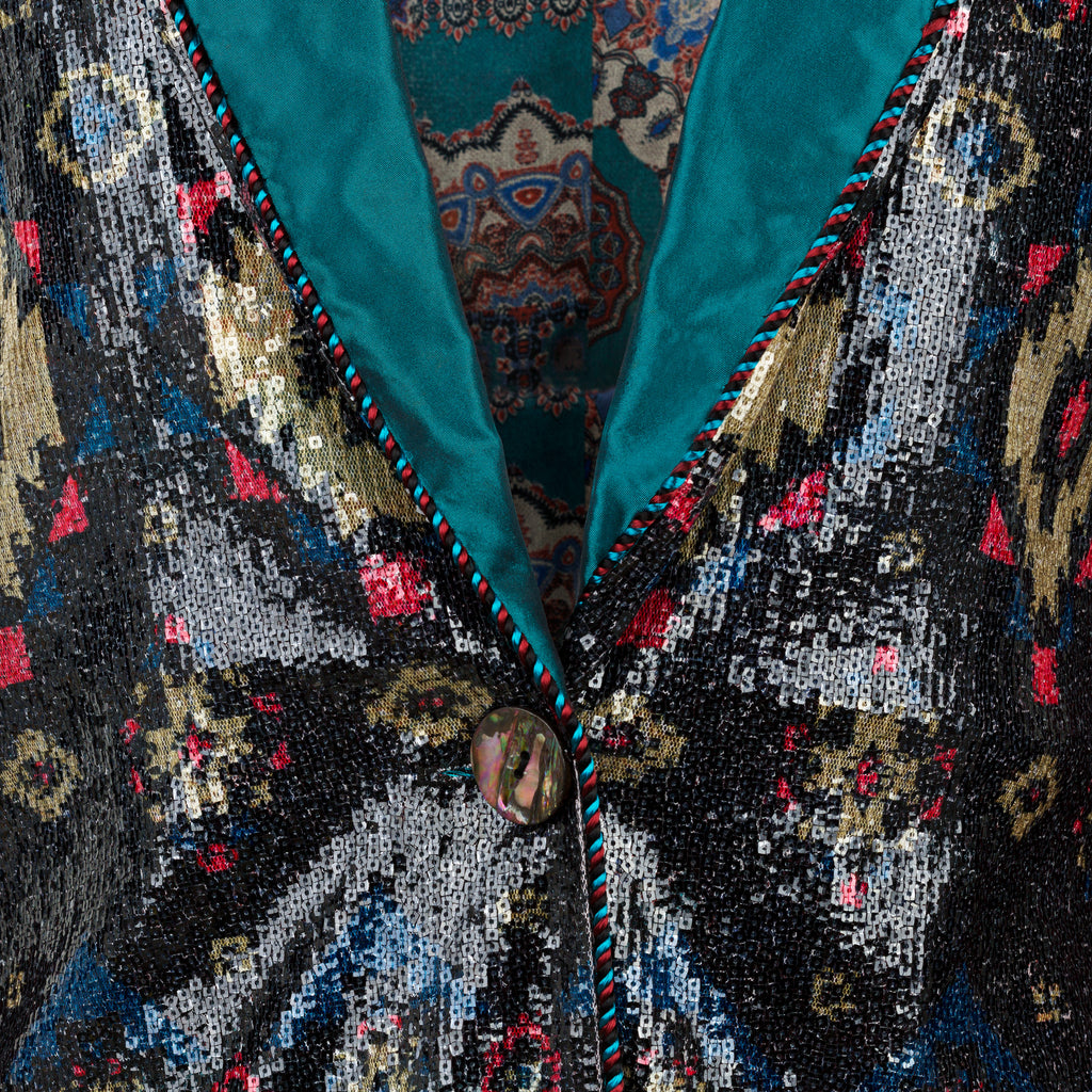 Close-up of a sequined garment with a button, featuring a multicolor pattern. Velvet sequins blazer — black velvet designer blazer with hand-stitched sequins from Laure Welfling Marrakech, limited edition