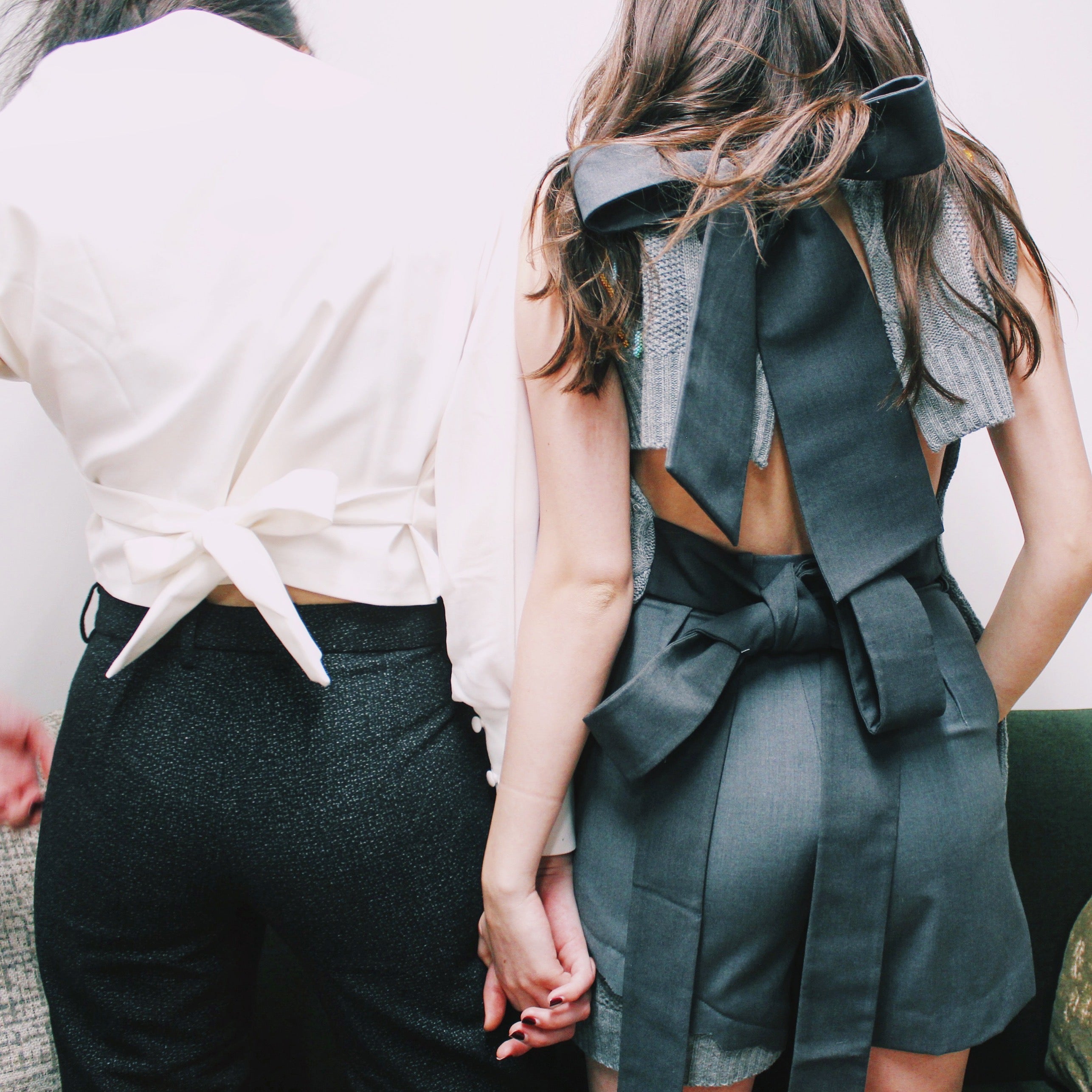 Two people holding hands, one wearing a green outfit with a large bow, the other in a white top and black pants. Wool embroidered vest — handmade wool designer vest with hand-embroidery from Patrick Owen Jakarta, relaxed fit, limited edition