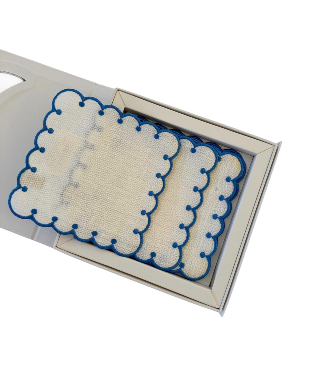 Set of coasters with blue scalloped edges in a decorative box on a white background