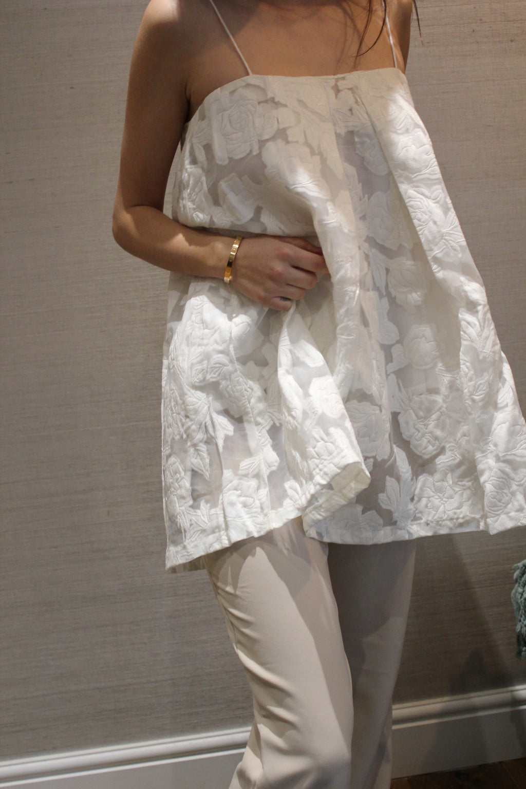 Person wearing a white floral dress over beige pants against a neutral background. Indonesian lace dress top — handmade lace designer top from Maryallé Jakarta, fitted, limited edition occasion piece