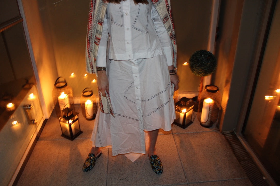 Person wearing a light-colored outfit with a patterned shawl in a dimly lit room with candles. Indonesian asymmetrical dress — handmade asymmetric designer dress from Major Minor Jakarta, relaxed fit, limited edition
