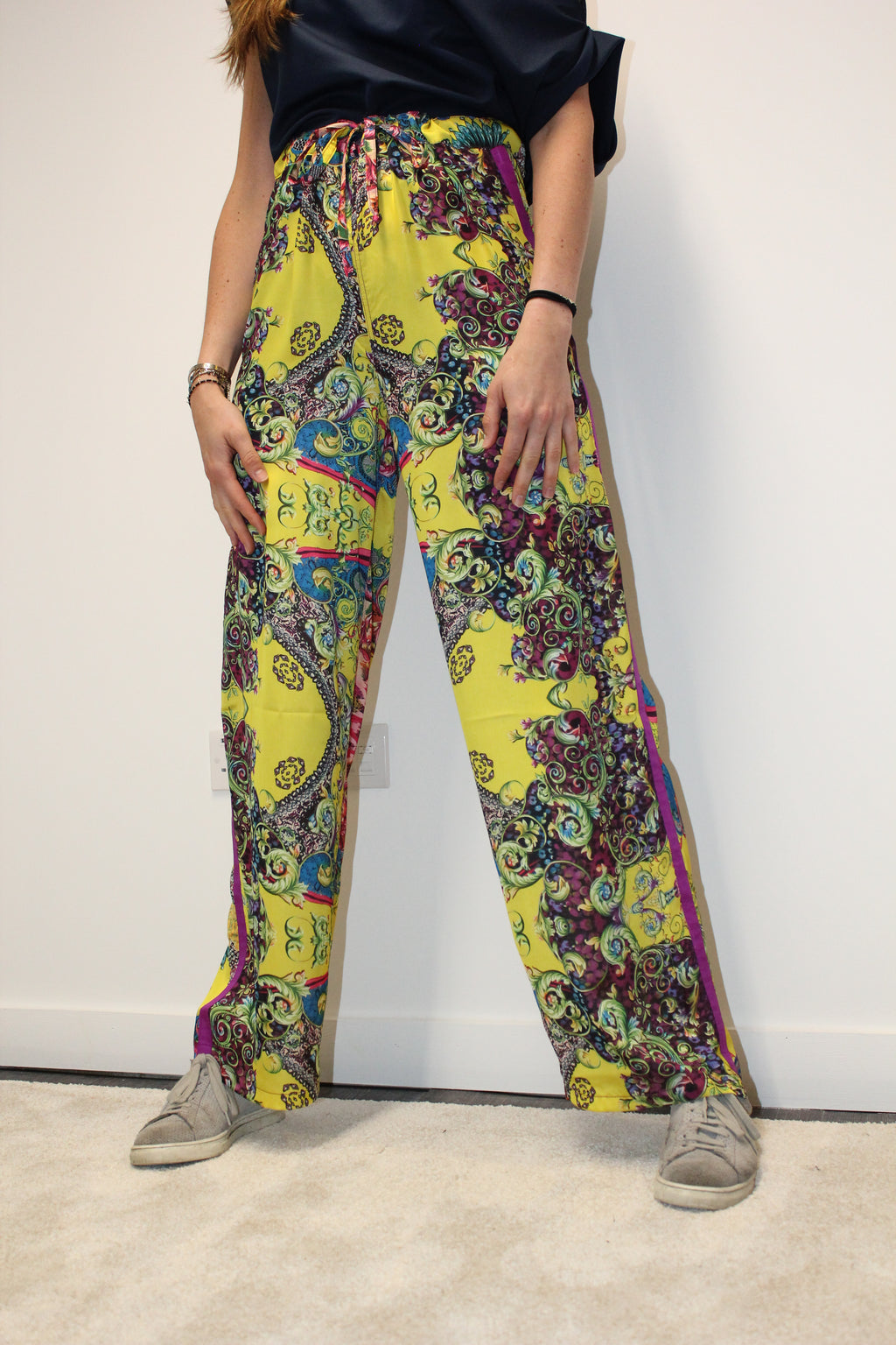 Colorful patterned leggings being displayed on a mannequin against a white background. Yellow patterned silk pants — handmade yellow silk designer pants with groovy print from Hanout Boutique Marrakech, relaxed fit