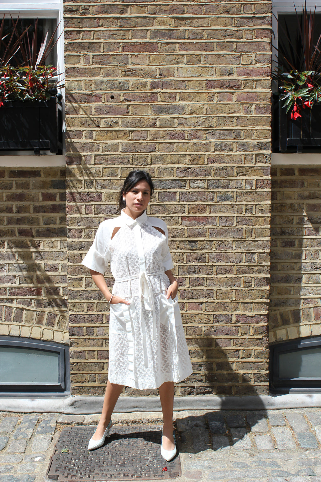 Person wearing a white dress standing on a brick pavement. Indonesian cool summer dress — handmade designer cotton summer dress from Major Minor Jakarta, relaxed fit, limited edition