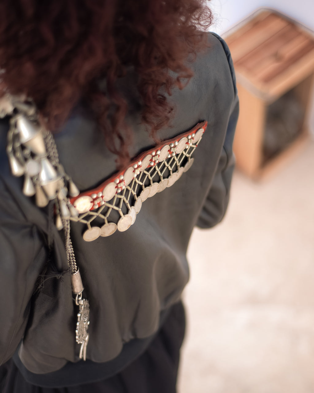 Close-up of a person wearing a dark green garment with intricate lace detailing and decorative elements. Jewelled biker jacket — handmade designer biker jacket with jewel detailing from Hanout Boutique Marrakech, fitted, limited edition