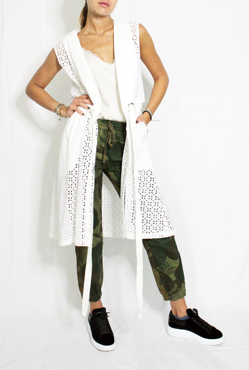 Person wearing a white long-sleeve top, green camouflage pants, and black sneakers on a white background. Indonesian cool summer vest — handmade designer cotton summer vest from Major Minor Jakarta, relaxed fit, limited edition