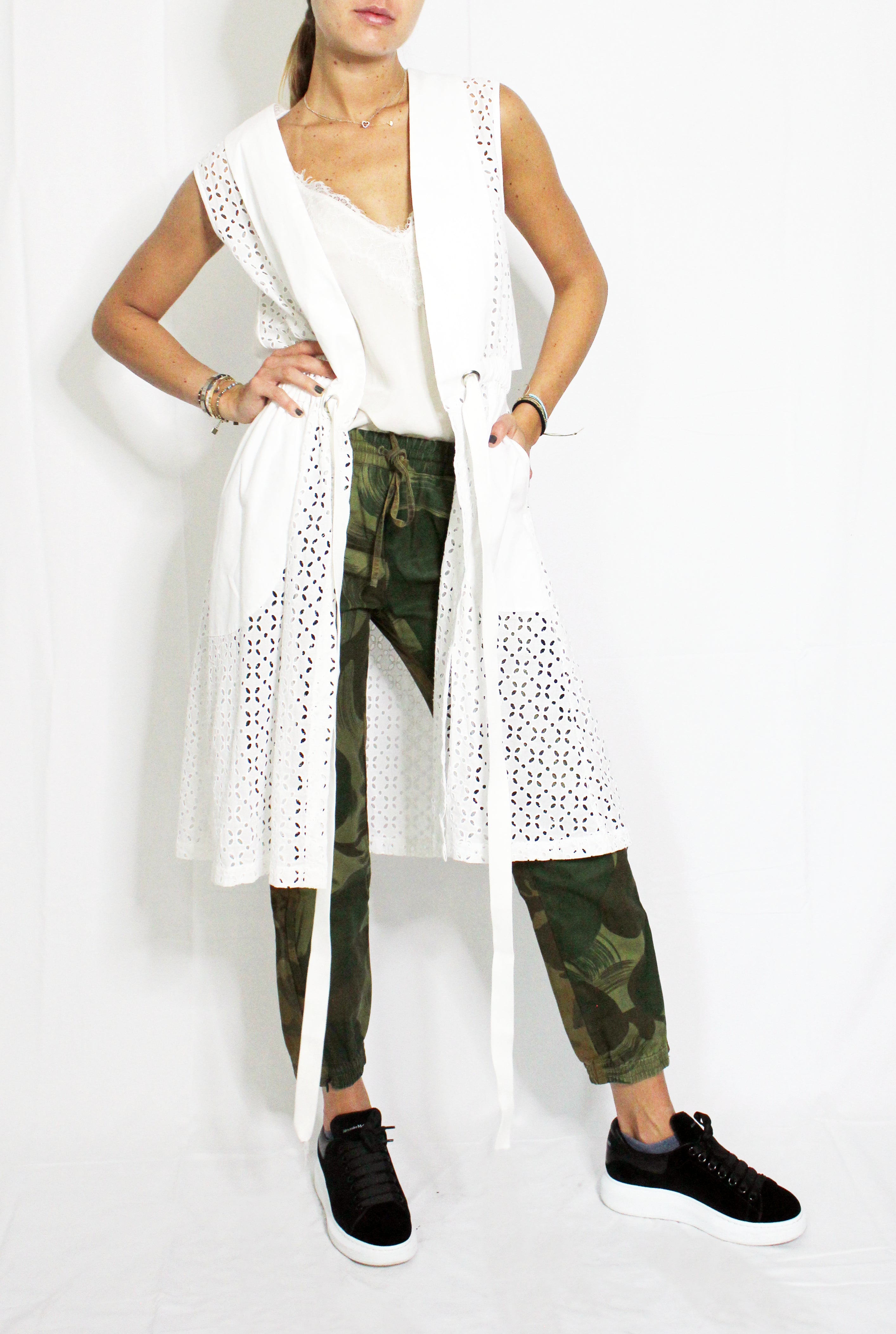 Person wearing a white long-sleeve top, green camouflage pants, and black sneakers on a white background. Indonesian cool summer vest — handmade designer cotton summer vest from Major Minor Jakarta, relaxed fit, limited edition