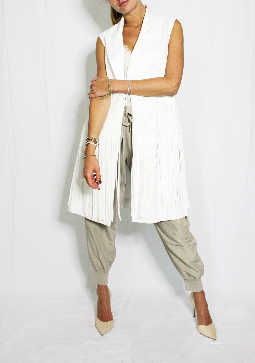 Woman wearing a white sleeveless top and beige pants on a white background. Indonesian stringy vest — handmade designer cotton vest with string detail from Major Minor Jakarta, relaxed fit, limited edition