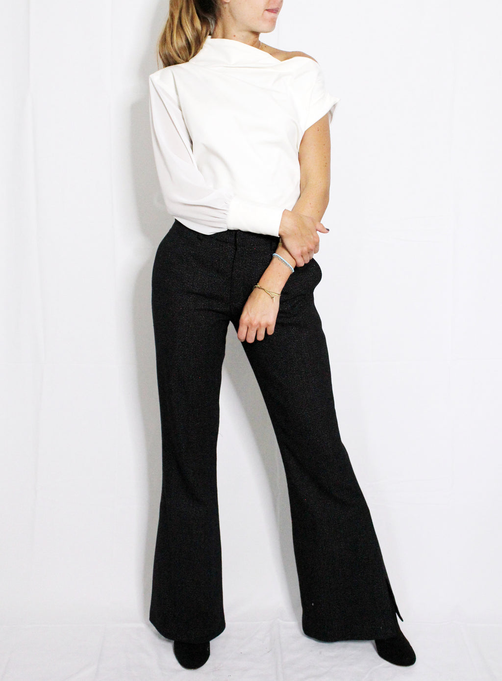Person wearing a white top and black flared pants on a white background. Indonesian asymmetrical shirt — handmade asymmetric designer shirt from Maryallé Jakarta, fitted, limited edition piece