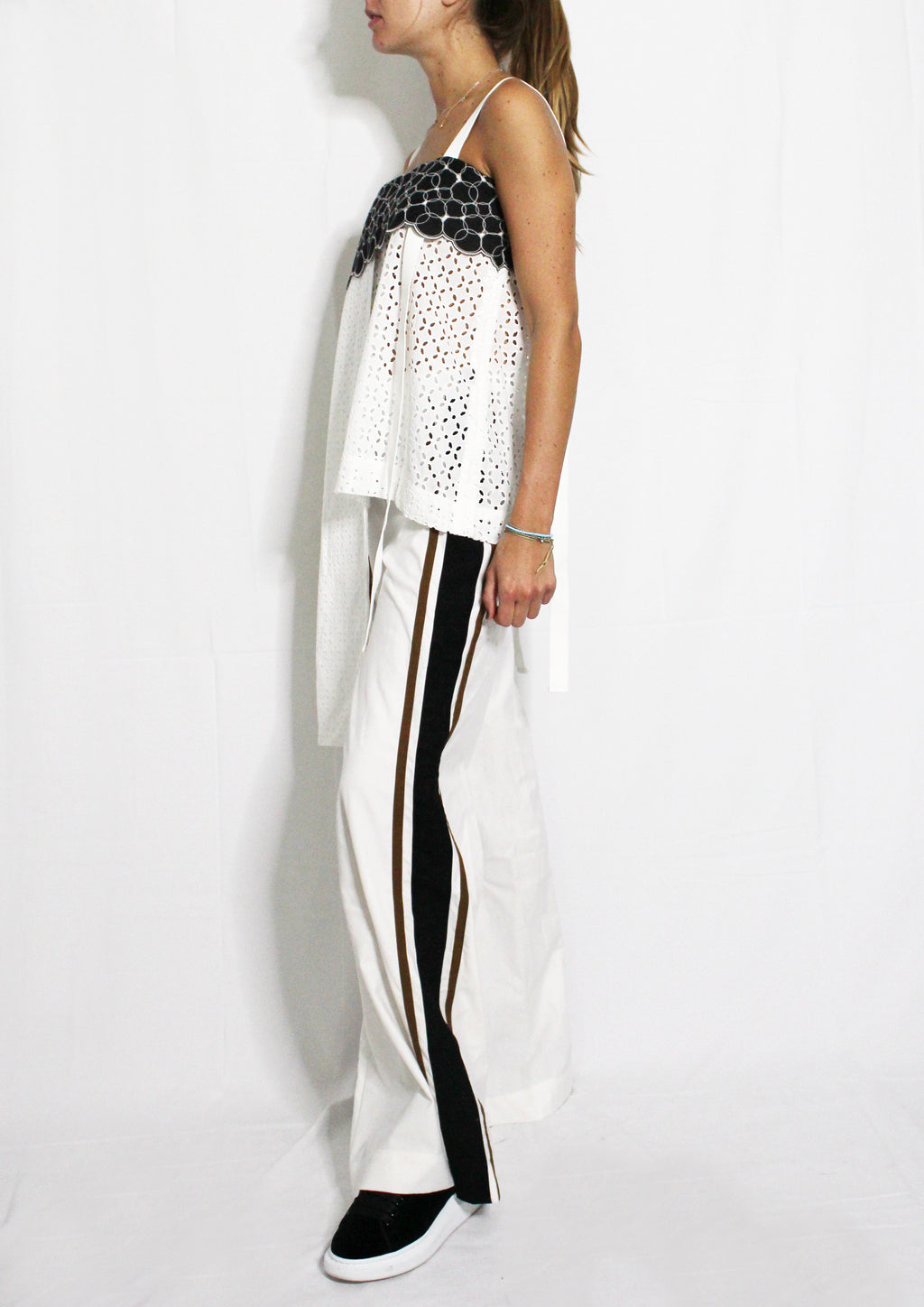 Woman wearing a white top with black and gold accents and black and white pants on a white background. Striped trousers — handmade designer striped cotton trousers from Major Minor Jakarta, relaxed fit, limited edition summer