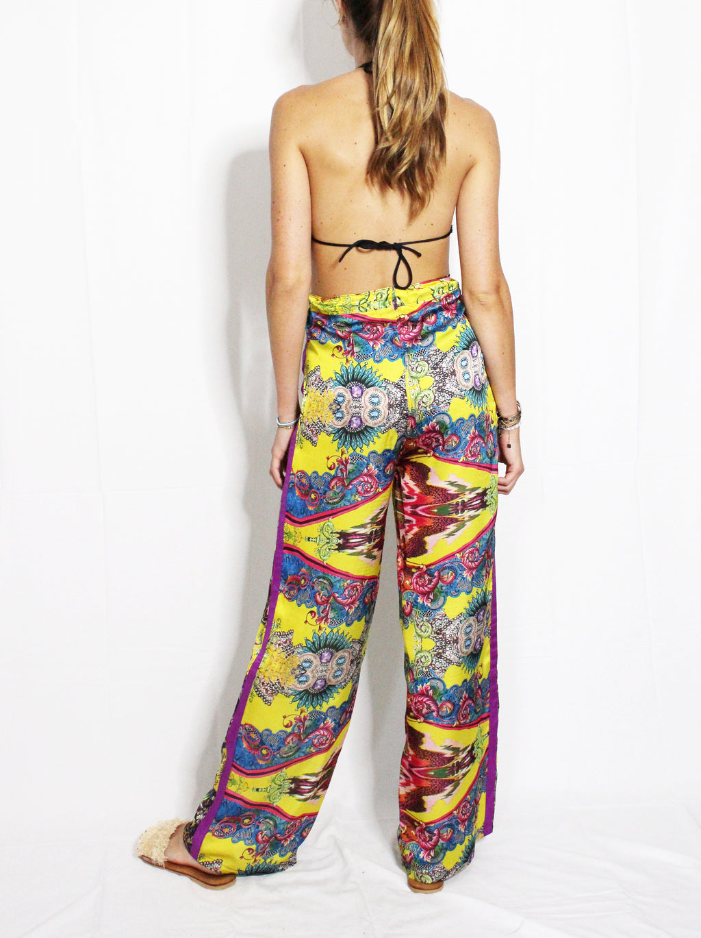 Person wearing colorful patterned pants on a white background. Yellow patterned silk pants — handmade yellow silk designer pants with groovy print from Hanout Boutique Marrakech, relaxed fit
