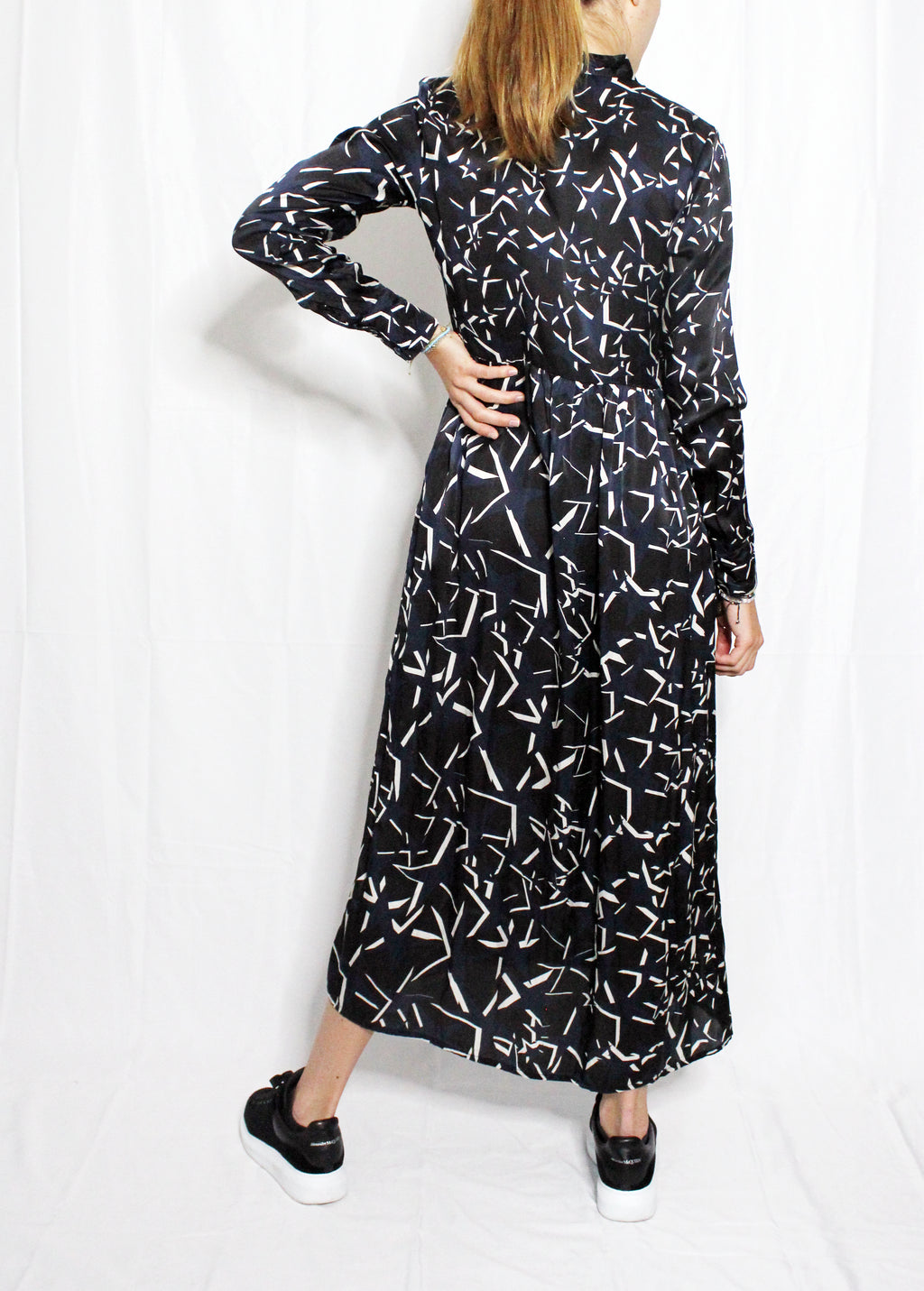 Woman wearing a black dress with white abstract patterns on a white background. Starry Night dress — handmade designer dress with starry print from Hanout Boutique Marrakech, fitted, limited edition occasion piece