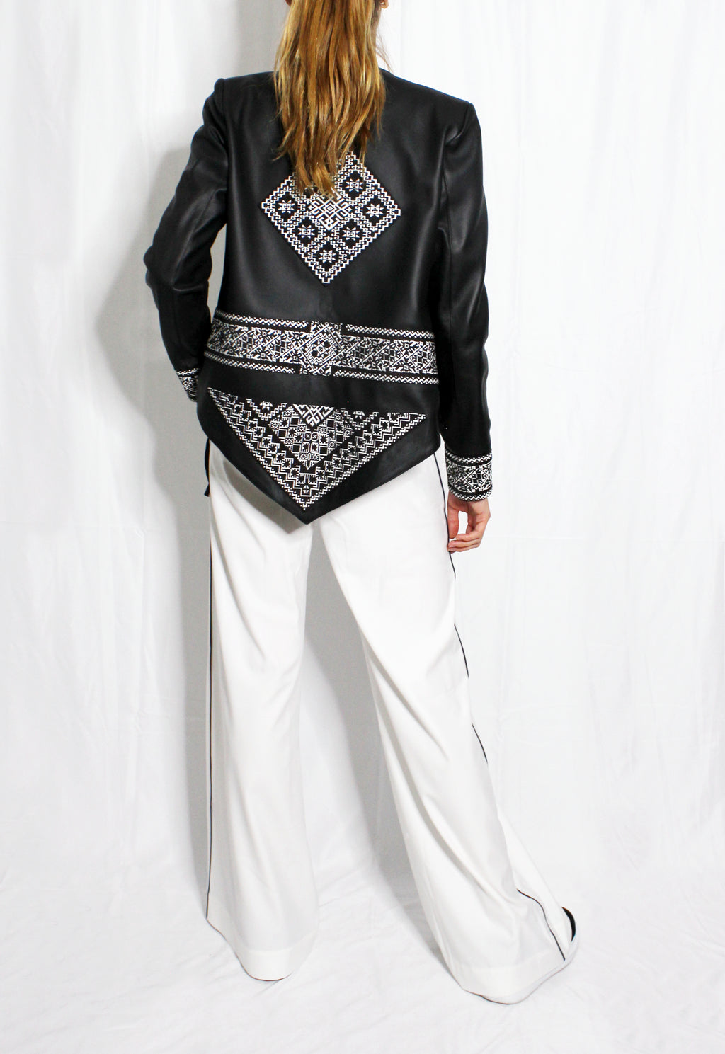 Person wearing a black jacket with white patterns and white pants on a white background. Extra loose trousers — handmade designer relaxed trousers from Major Minor Jakarta, oversized fit, limited edition summer