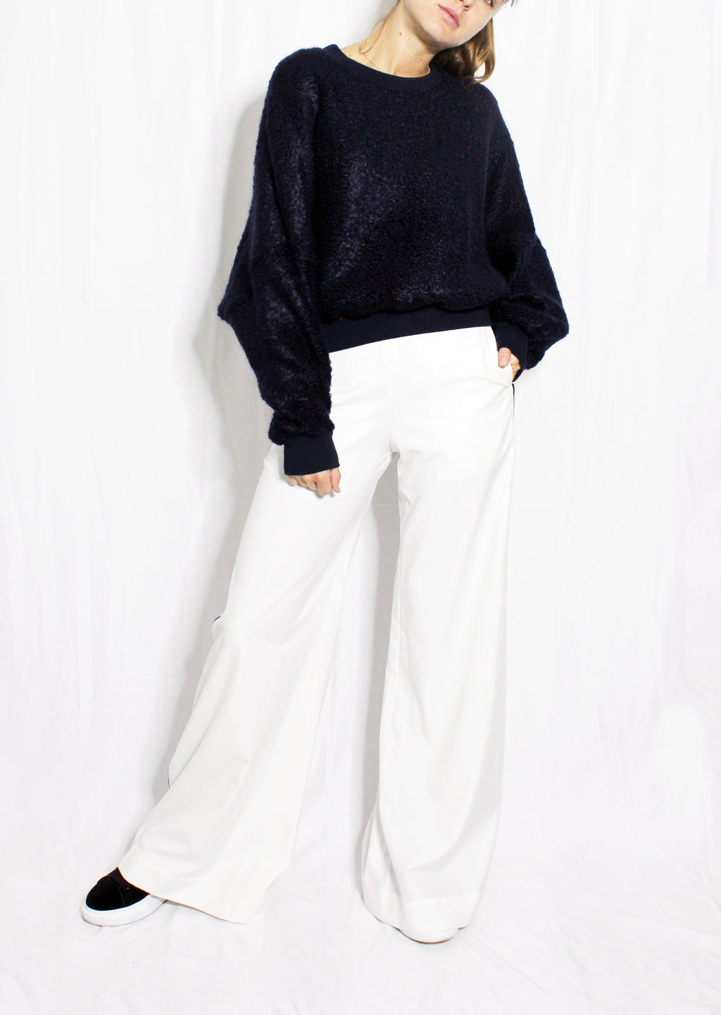 Person wearing a navy sweater and white pants on a white background. Navy wool cashmere jumper — handmade navy wool blend designer jumper from Hanout Boutique Marrakech, relaxed fit, limited edition