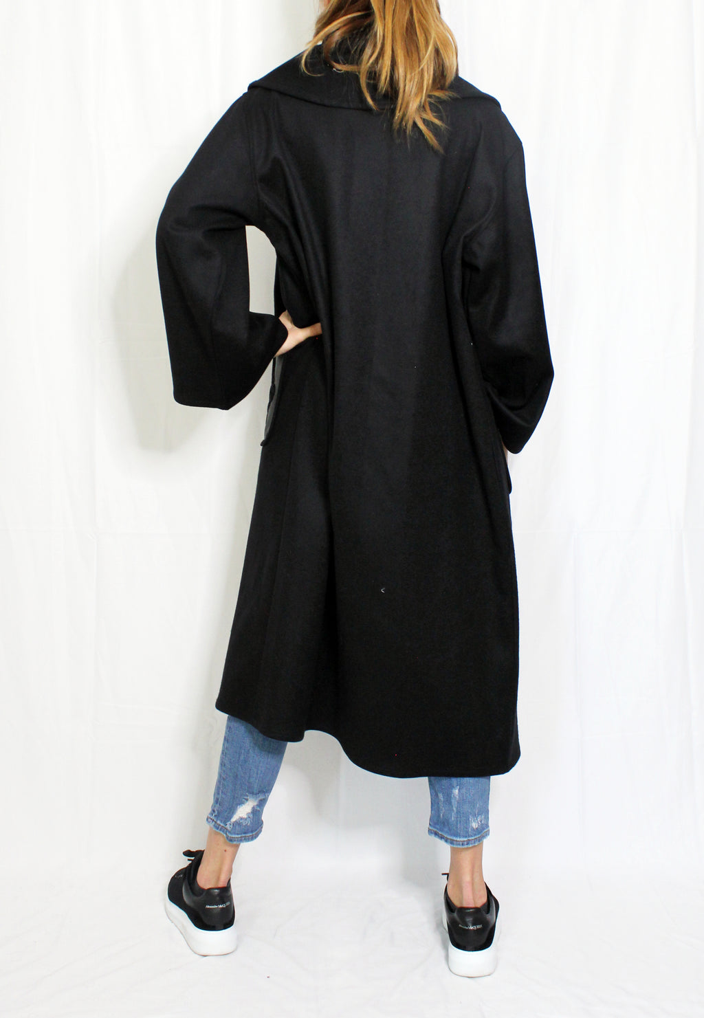 Person wearing a black coat with a white background. Wool embroidered coat — heavy wool designer coat with hand-embroidered detail from Hanout Boutique Marrakech, limited edition