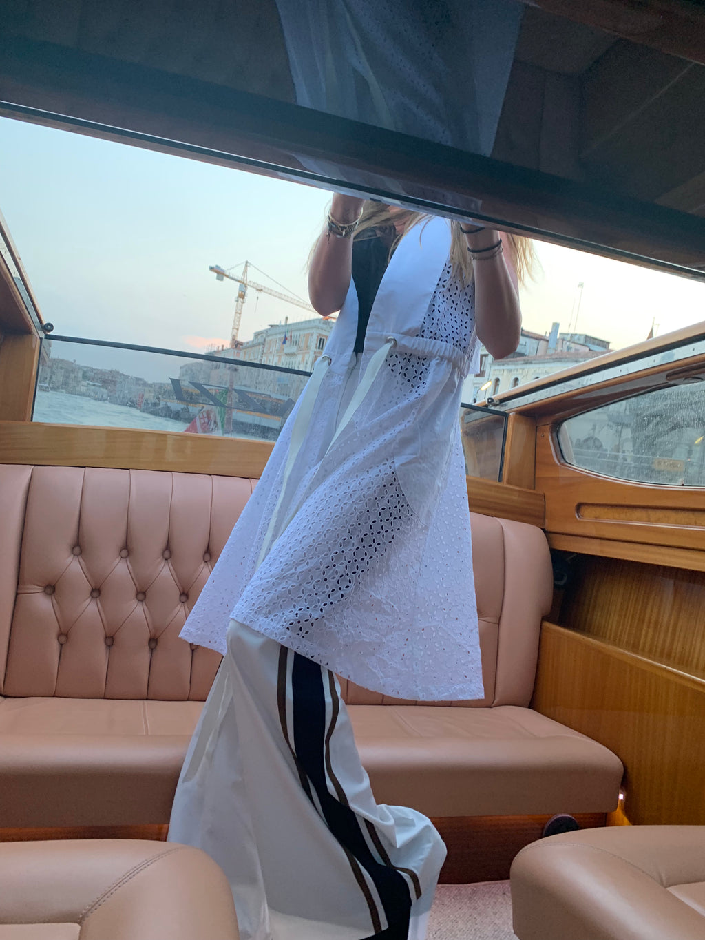 Person holding a white dress with black polka dots inside a vehicle. Striped trousers — handmade designer striped cotton trousers from Major Minor Jakarta, relaxed fit, limited edition summer. Indonesian cool summer vest — handmade designer cotton summer vest from Major Minor Jakarta, relaxed fit, limited edition