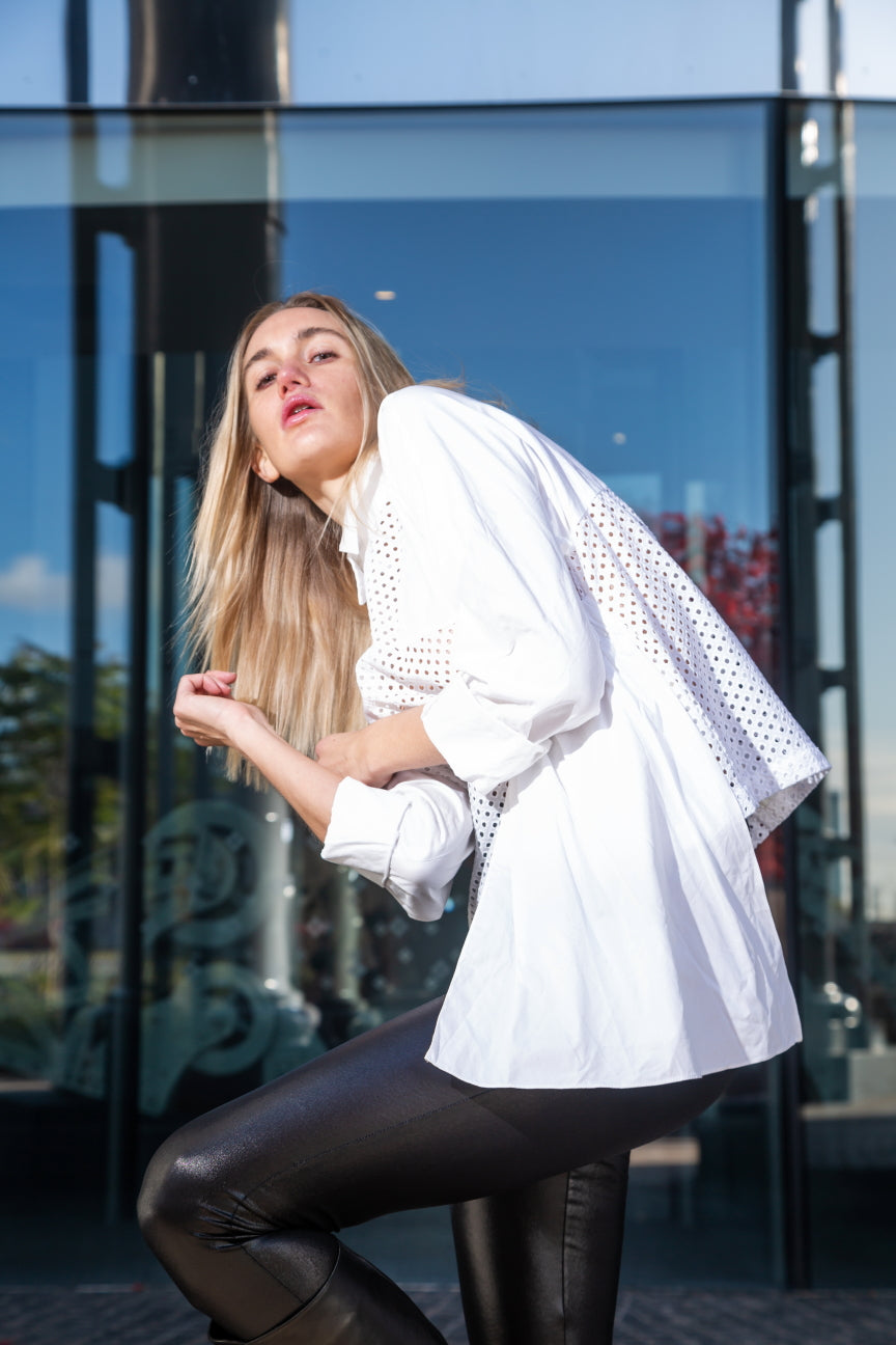 Woman wearing a white blouse and black pants posing outdoors. White dotted blouse — handmade white designer blouse with delicate dot print from Major Minor Jakarta, relaxed fit, limited edition