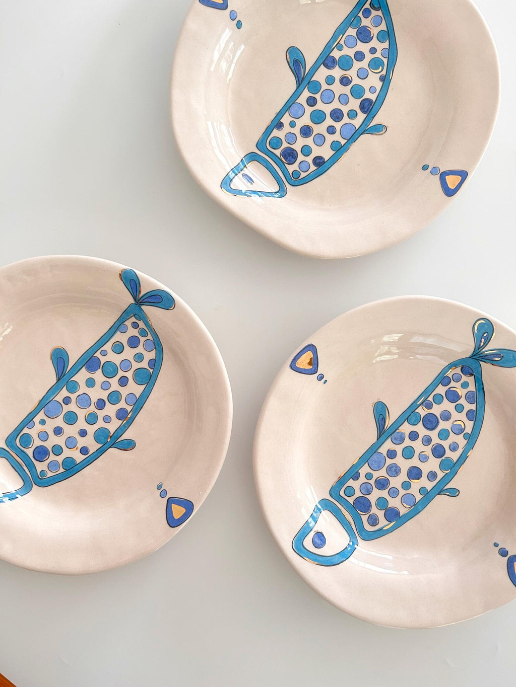 Three ceramic plates with blue fish designs on a white background
