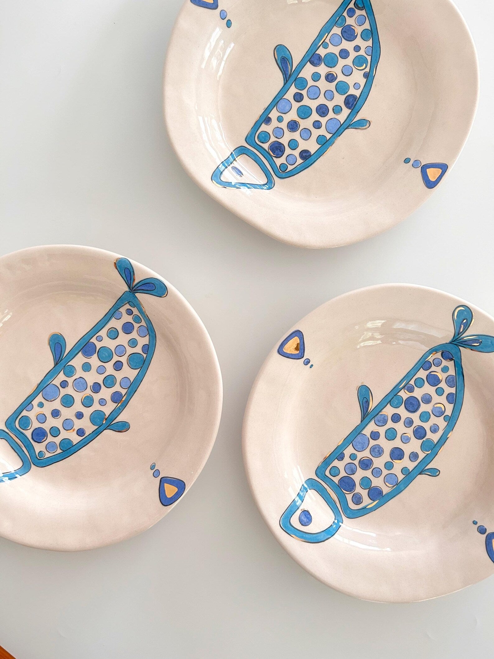 Three ceramic plates with blue fish designs on a white background