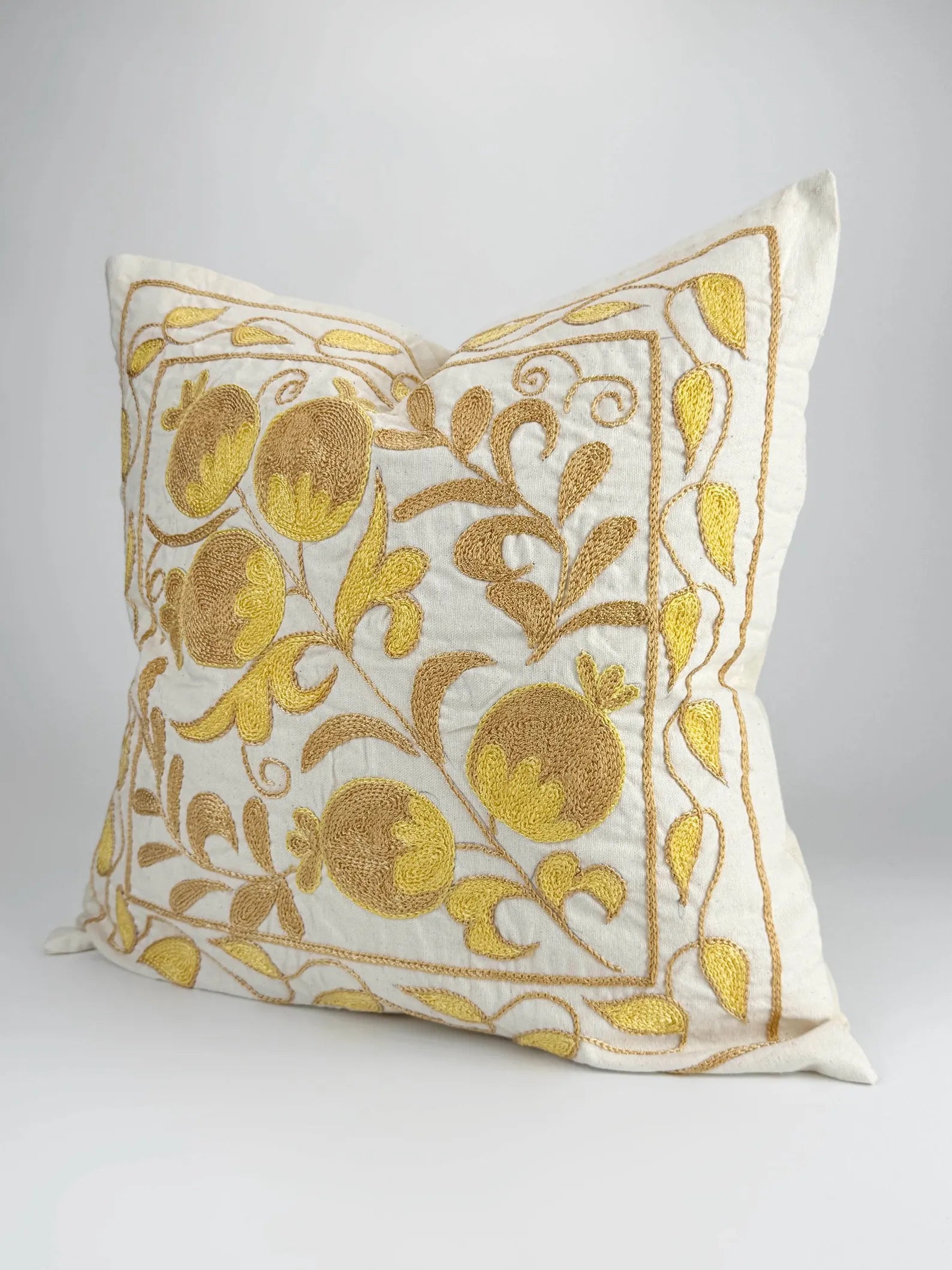 Decorative pillow with gold floral embroidery on a white background