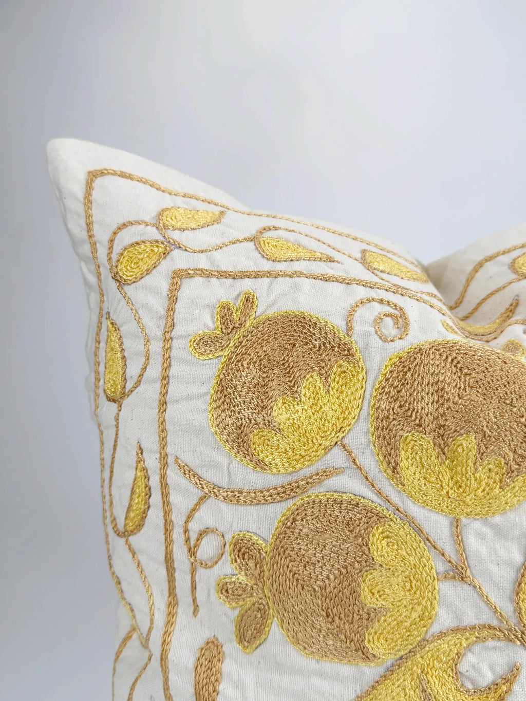 Decorative pillow with gold embroidery of pomegranates on a white background