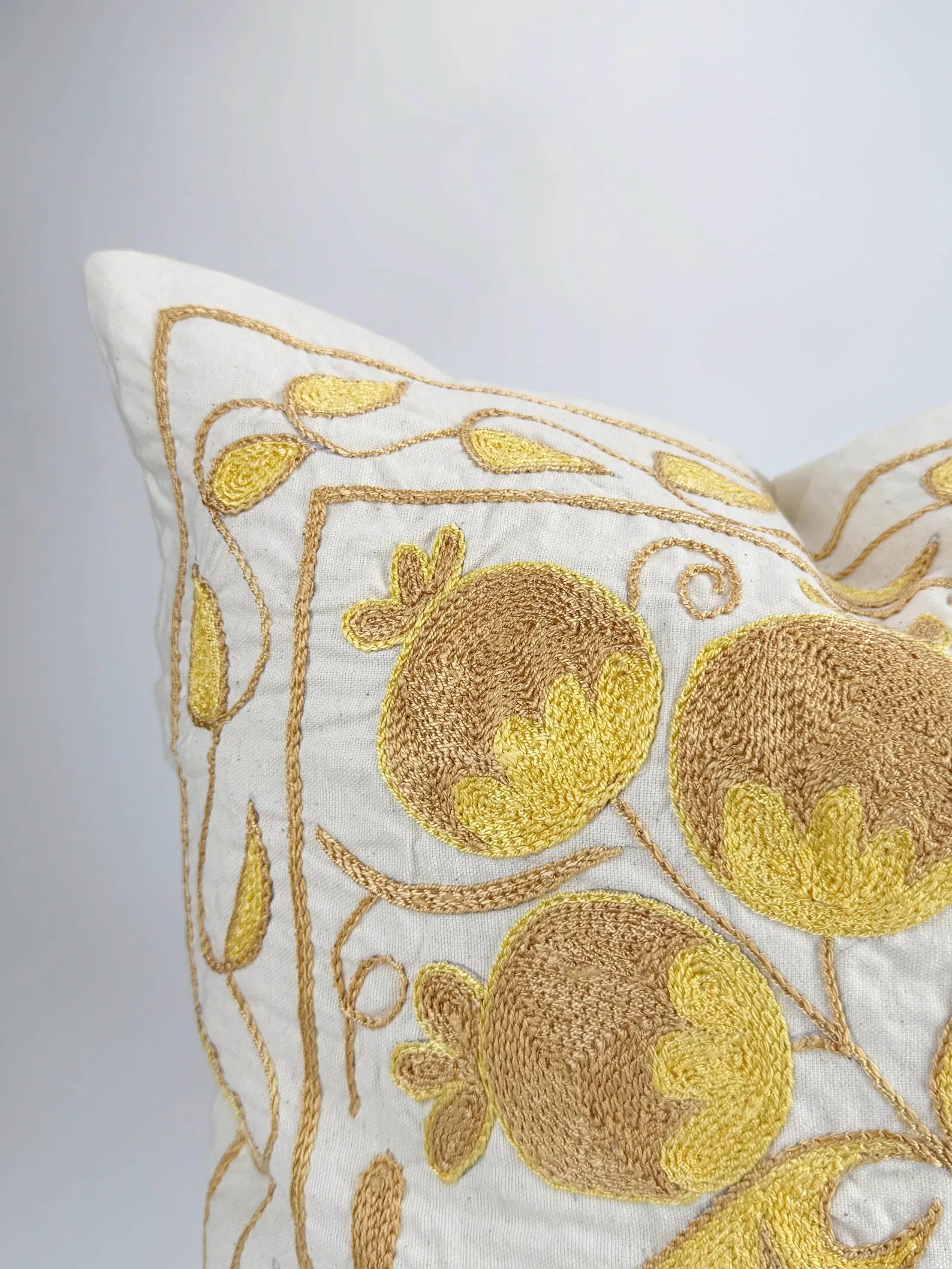 Decorative pillow with gold embroidery of pomegranates on a white background