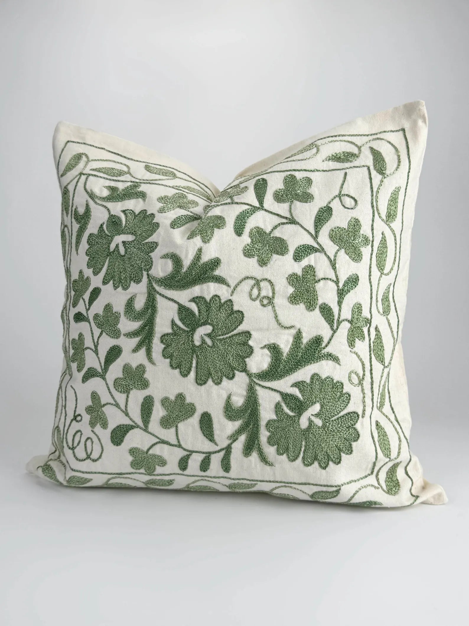Decorative pillow with green floral pattern on a white background