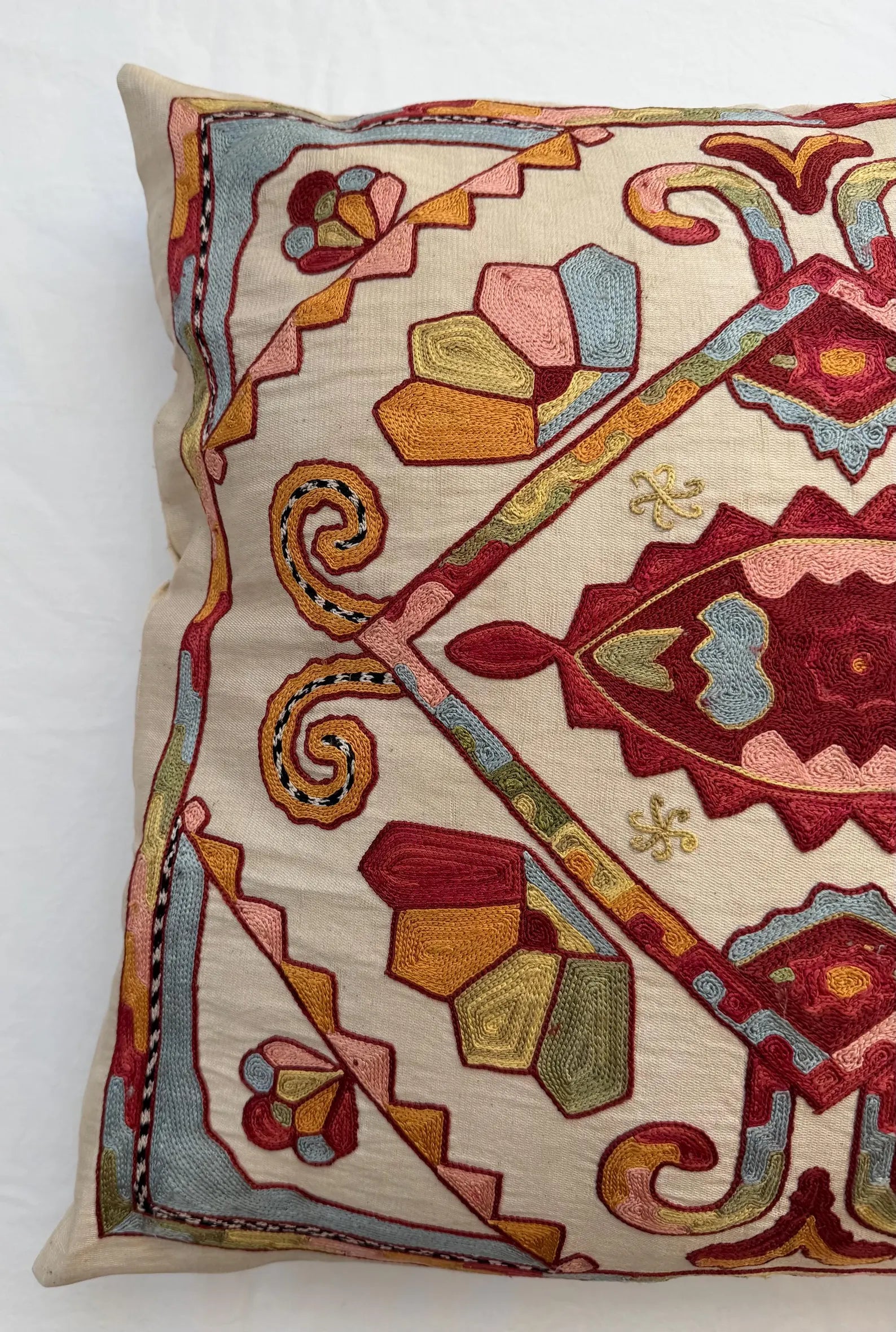 Decorative pillow with intricate patterns and colors on a white background